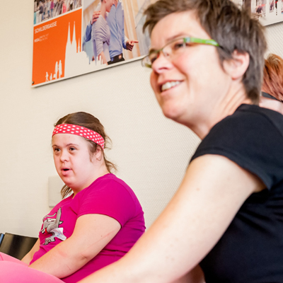 Rosa Schneider und eine andere Person sitzen und hören zu.