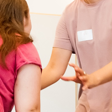 Eine Person hebt schützend die Person vor einer anderen Person.